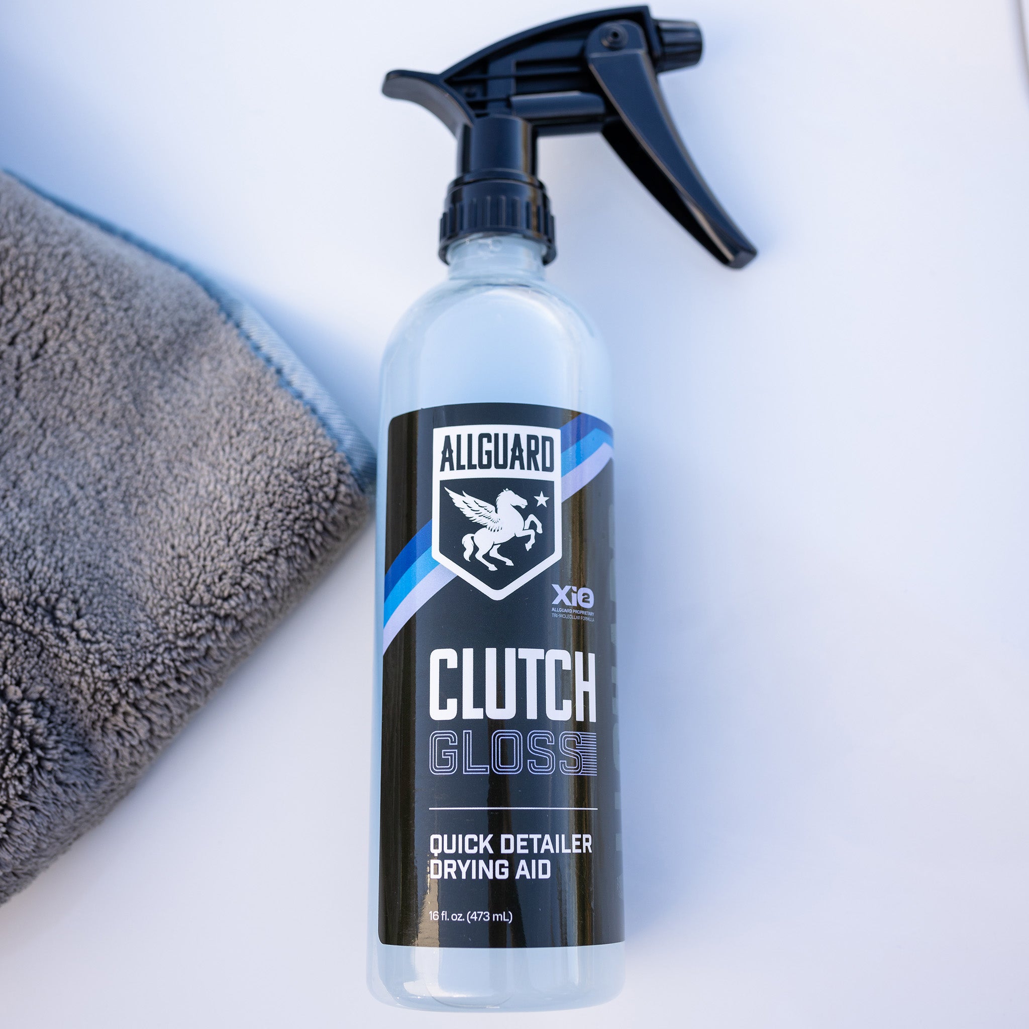 Bottle of Clutch Gloss quick detailer and drying aid laying near microfiber towel