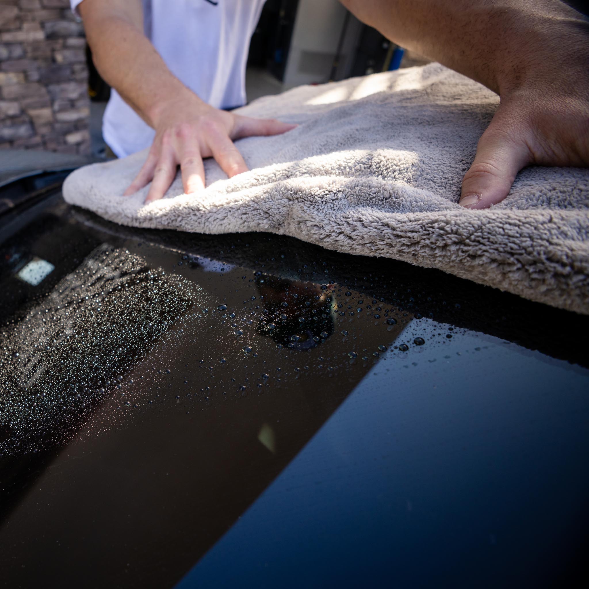 Man uses dry towel on rear of car