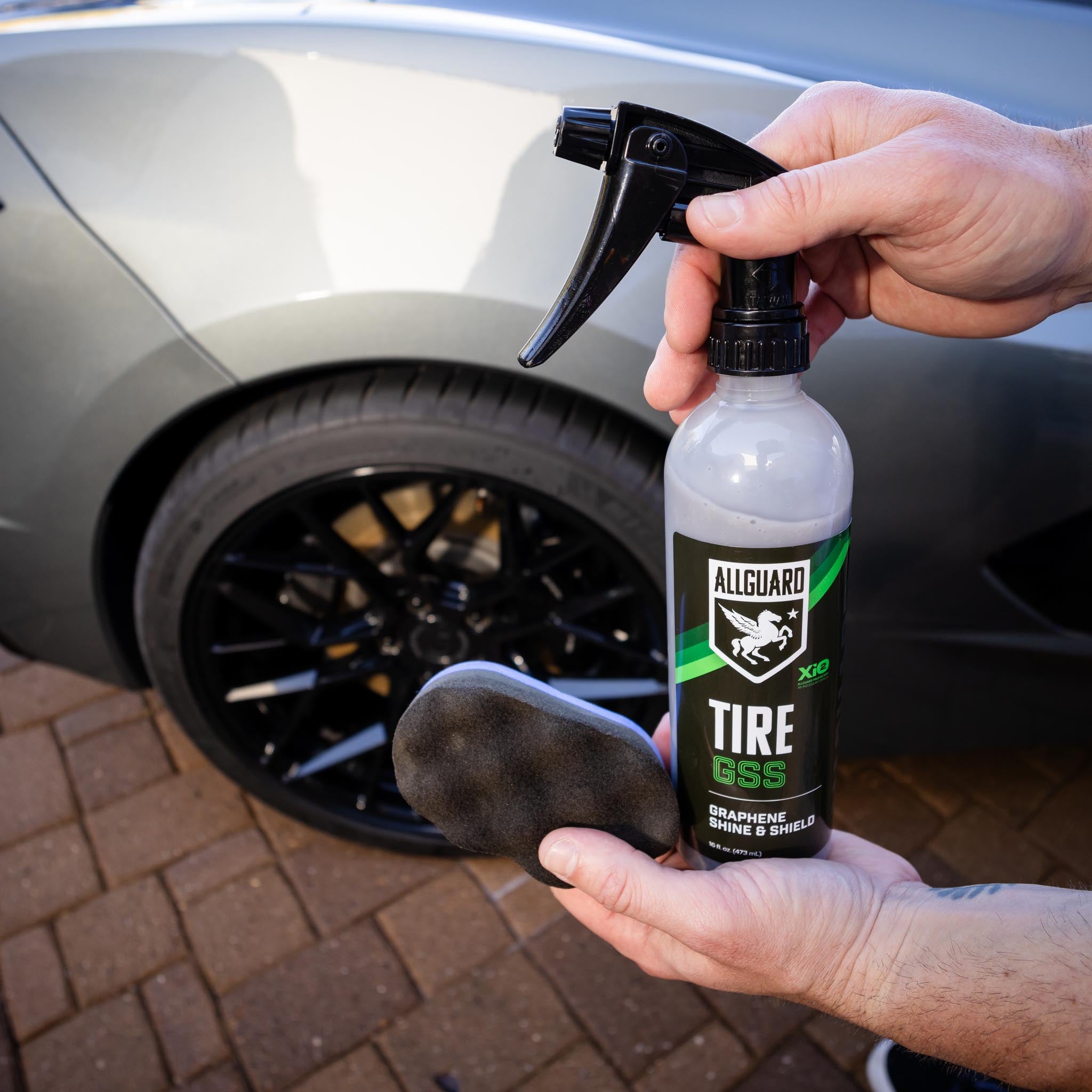 Man holds tire coating and scrubber up to camera