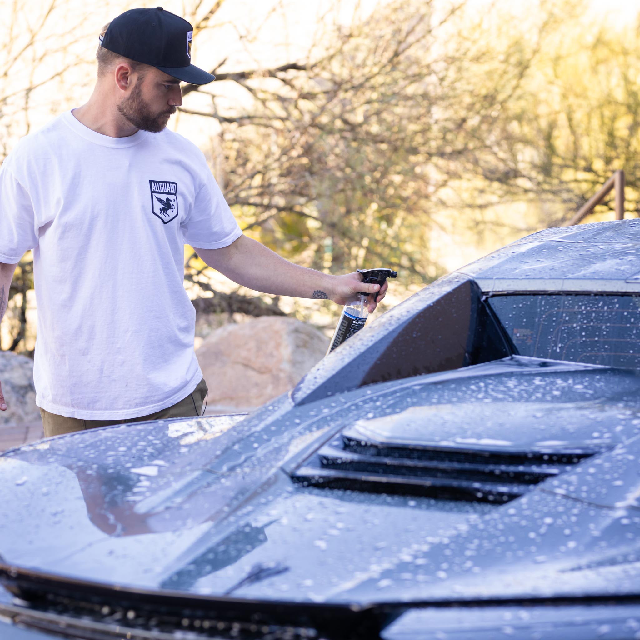 Man spraying product on car with rear window and diffuser in foreground