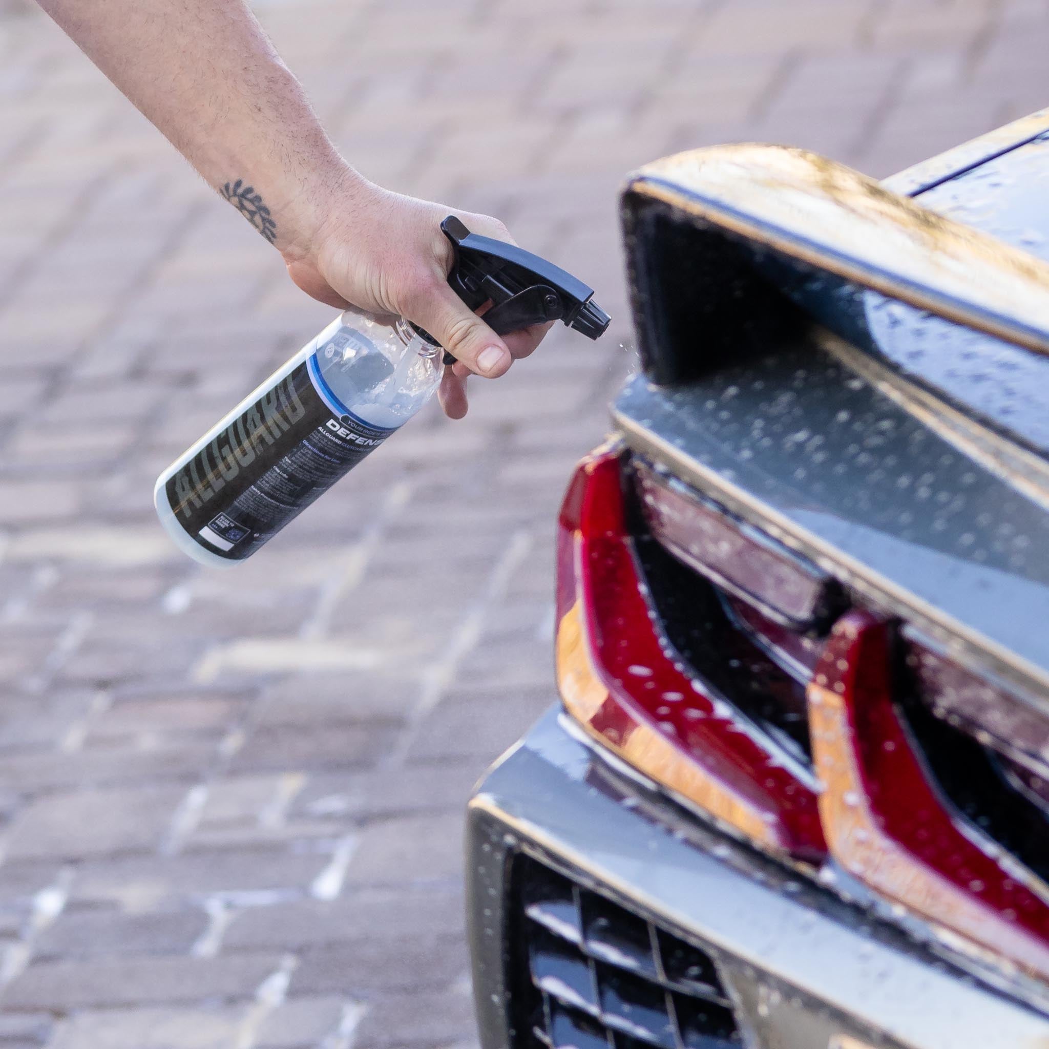 Man spraying a car detailing product on rear spoiler