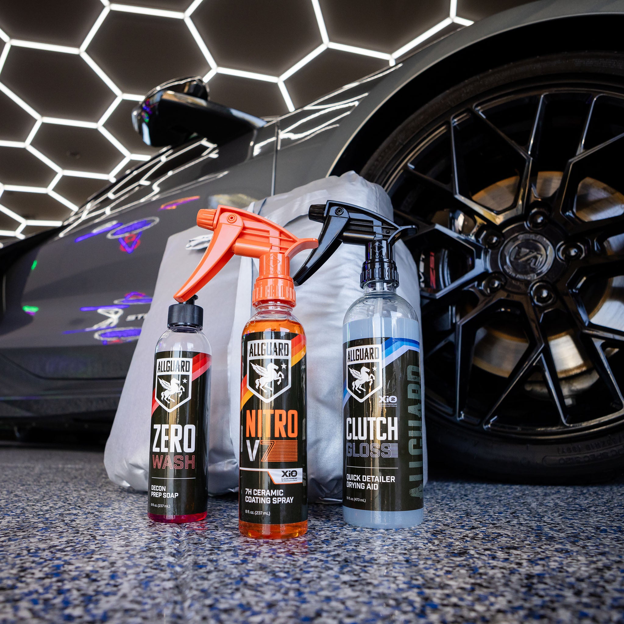 Several components of AllGuard's car detailing kit on ground in front of back tire