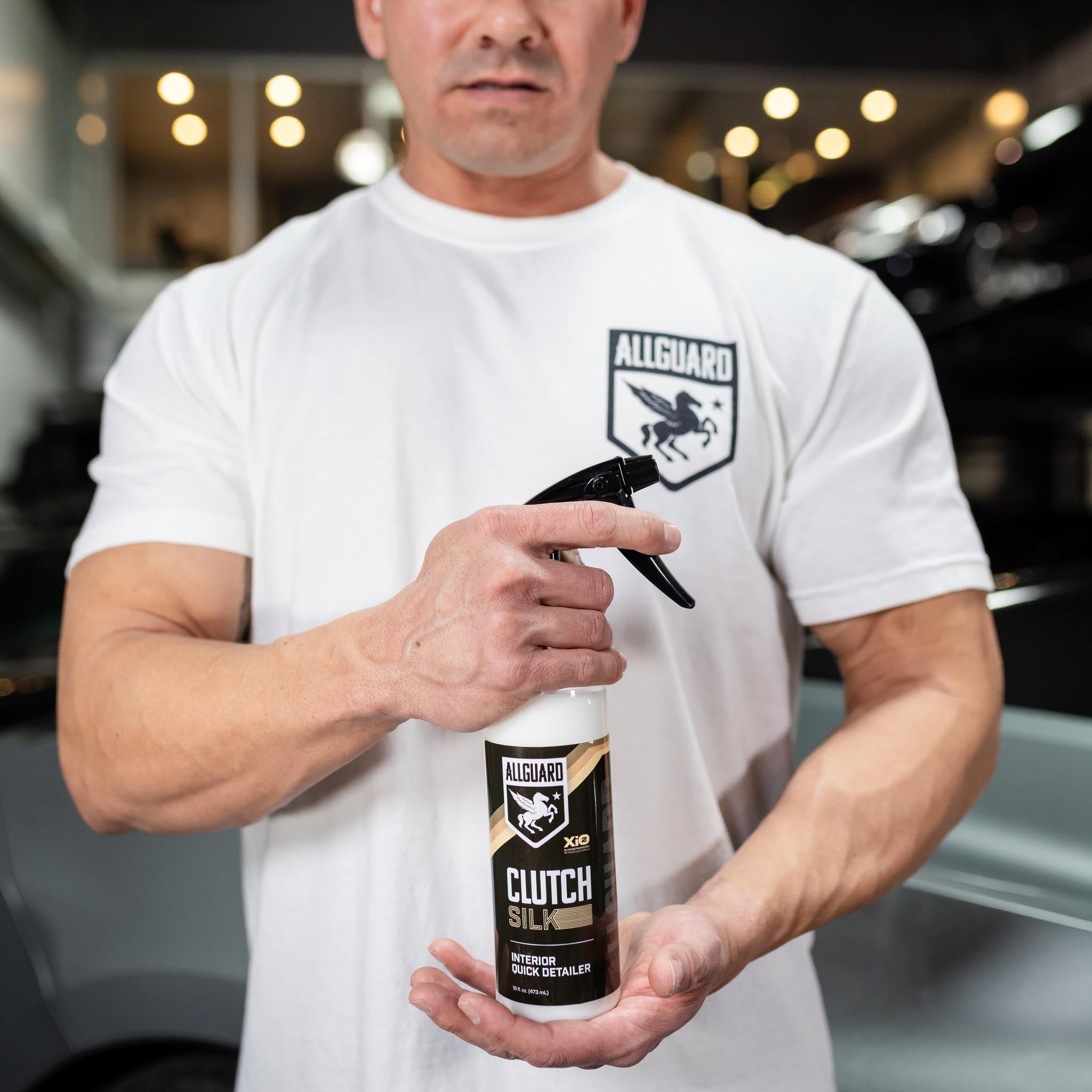 Muscular man in white shirt holds interior detailer close to camera