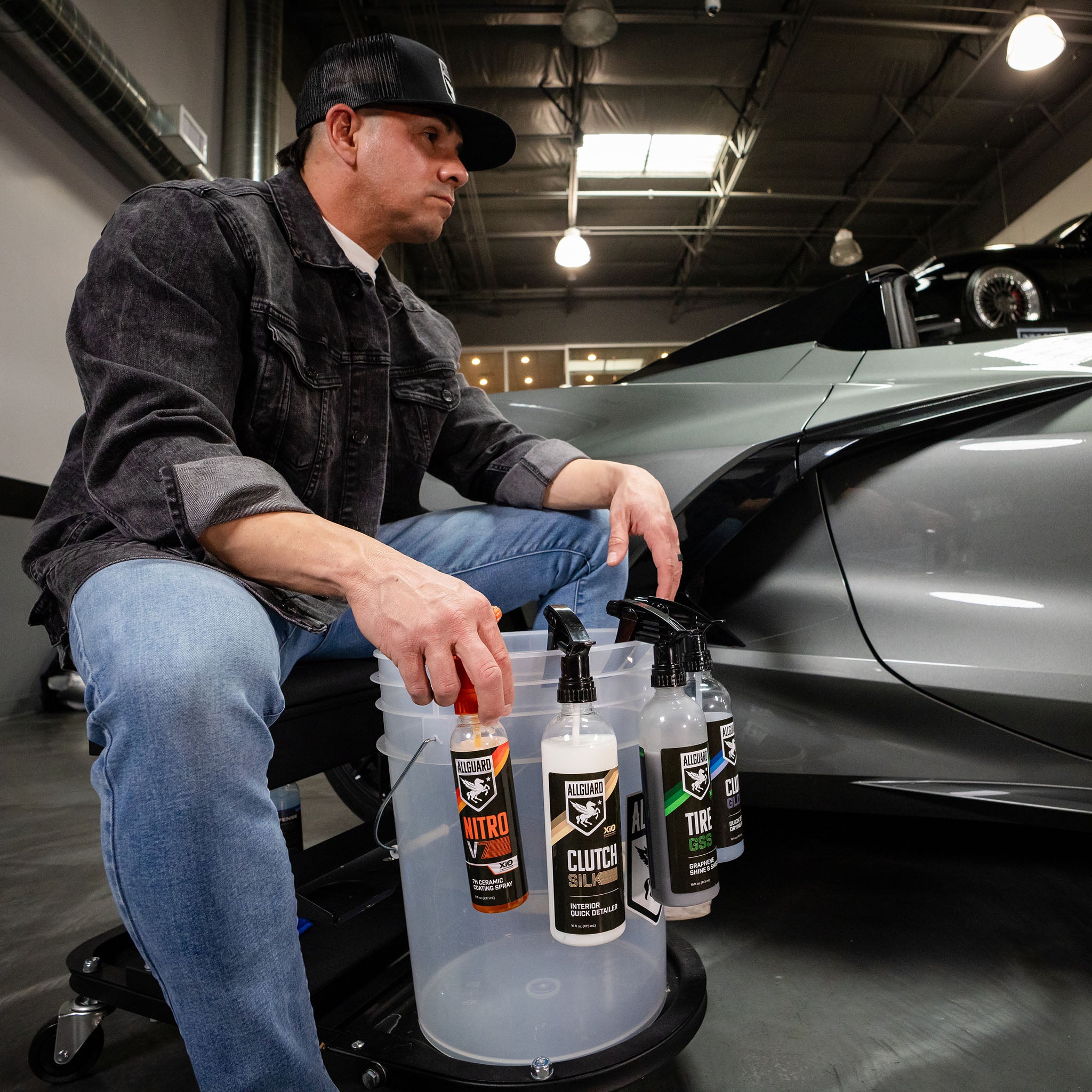 Sitting man looks at car with detailing kit and empty bucket