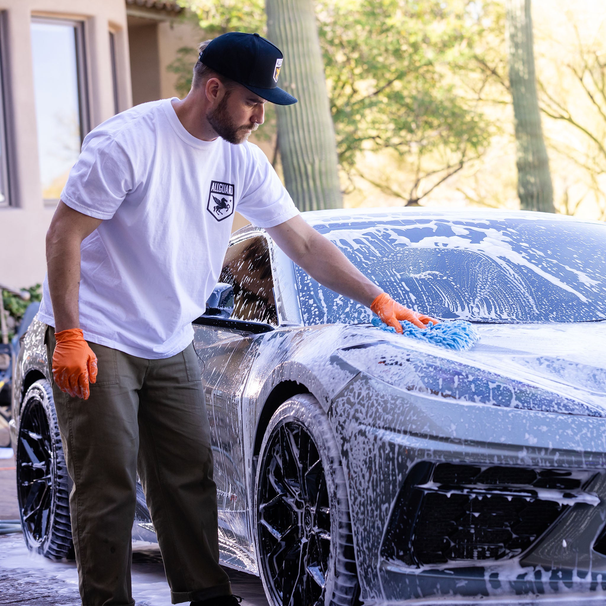Man does shampoo wash on car hood with microfiber sponge