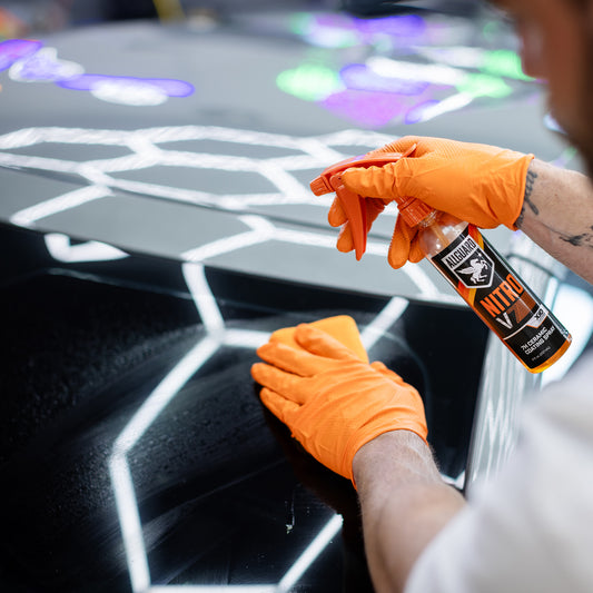 Ceramic coating spray being applied to car hood in a garage