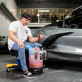 Man in chair prepping for exterior car detailing with various solutions
