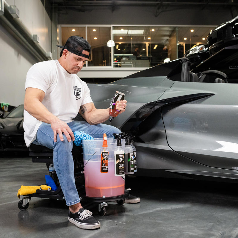 Man in chair prepping for exterior car detailing with various solutions